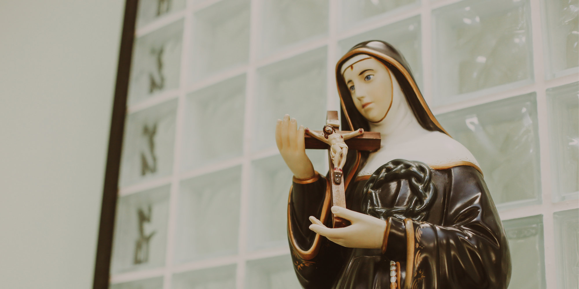 Statue of Saint RIta with thorn wound in her foreheard holding a crucifix in a habit.